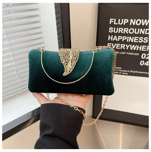 Close-up of green velvet evening clutch bag featuring a gold leaf metal clasp and chain