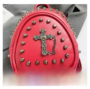 Détail d'un sac à dos en cuir rouge avec clous argentés et pendentif croix gothique