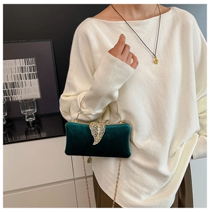 Detail of dark green velvet evening clutch bag with gold leaf buckle and chain
