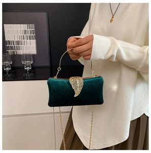 Detail of emerald velvet evening clutch bag with golden leaf buckle and metal chain strap