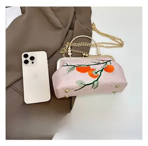 Detail showing pink embroidered handbag with retro clasp and size comparison to phone