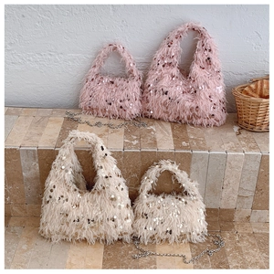 Detailed set of fluffy sequins handbags in pink and beige on stone stairs