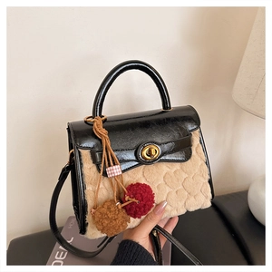 Close-up of beige fleece handbag with embossed heart texture and dual pompom charm