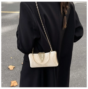 Detail of champagne gold velvet evening clutch with a large gold leaf buckle and chain strap
