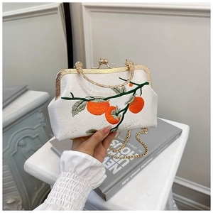 Détail de la broderie de persimmon et fermoir doré sur une pochette de soirée chic