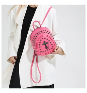 Détail d'un mini sac à dos en cuir rose avec rivets argentés et pendentif en croix