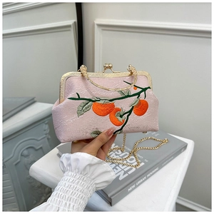 Détails de broderie de kaki orange sur sac en soie rose avec bandoulière dorée
