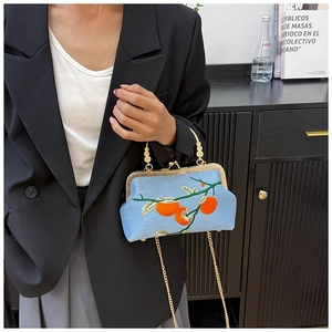 Close-up of light blue embroidered handbag with gold metal frame and chain strap