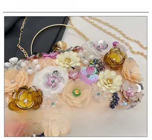 Close-up of 3D sequin flower embellishments and gold chain strap on dinner clutch bag