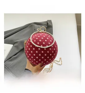 Detail of red polka dot ball clutch with crystal ring handle and gold chain strap