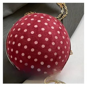 Detail of red suede sphere bag with pink polka dots and gold chain strap