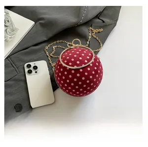 Chic red polka dot sphere handbag with diamond-encrusted metal handle and gold chain strap
