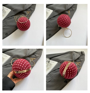 Detail of red polka dot spherical bag with gold round handle and fine chain strap