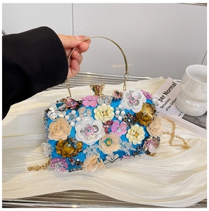 Detailed close-up of 3D floral embroidery with sequins and pearls on a royal blue clutch