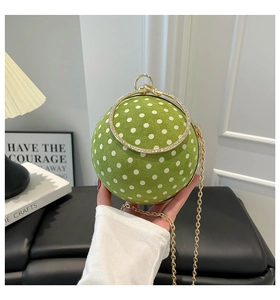 Close-up of green polka dot spherical bag with crystal handle and gold chain strap