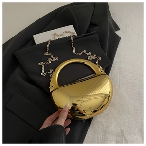 Détail d'un sac de soirée doré effet miroir avec poignée ronde et bandoulière
