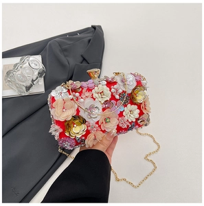Detail view of red evening clutch featuring 3D flowers, sequins, and golden ring handle