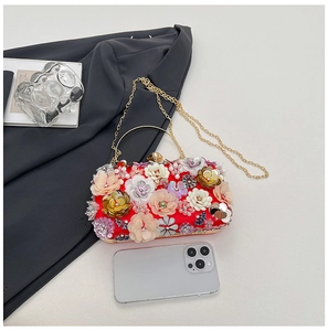 Macro view of luxurious red evening clutch with 3D floral embroidery and gold hardware