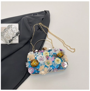 Macro shot of 3D floral appliques and gold metal hardware on blue satin evening clutch bag