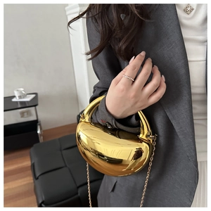 Gros plan d'un sac de soirée doré de forme irrégulière avec une finition miroir brillante