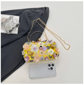 Detail of floral evening bag with colorful silk flowers and gold metal handle