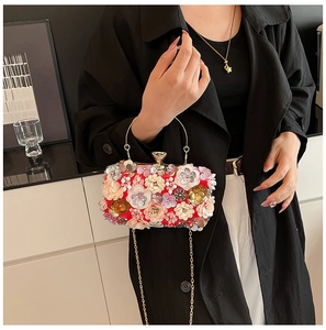 Detail of red floral evening bag with 3D petals and pearls on model with chain strap