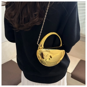 Détail d'un sac à main métallique doré brillant avec poignée intégrée et bandoulière chaîne