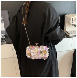 Detail of floral evening clutch bag with 3D resin petals and gold chain worn by model