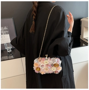 Detailed view of floral evening clutch bag with colorful 3D blossoms and gold chain strap