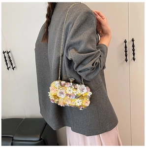 Detail of floral evening clutch featuring 3D handmade flowers and gold chain strap