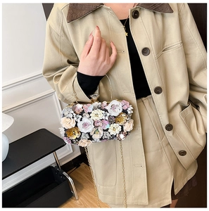 Detail of floral evening bag with gold ring handle and sparkling gemstone clasp