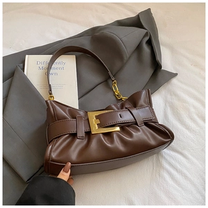 Detail of pleated cloud bag with large gold buckle on brown leather underarm strap