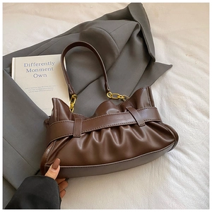 Detail of dark brown cloud bag with pleats and elegant gold metal chain hardware