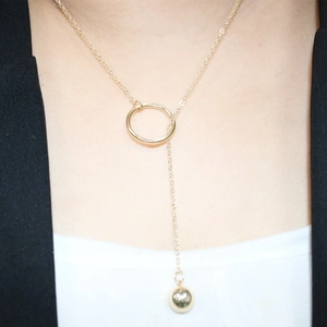Detail of gold Y-shaped necklace featuring a geometric circle and polished ball pendant