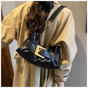 Detail of black pleated cloud bag with a large gold square buckle and chain strap
