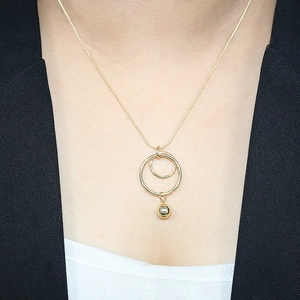 Close-up of geometric double circle pendant with metal bead on gold necklace