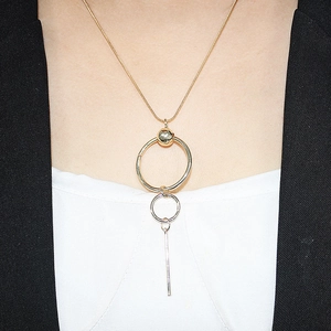 Detail view of geometric long pendant necklace with layered gold rings and silver bar