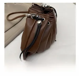 Close-up of pleated dark brown leather dumpling bag with silver eyelets and drawstring