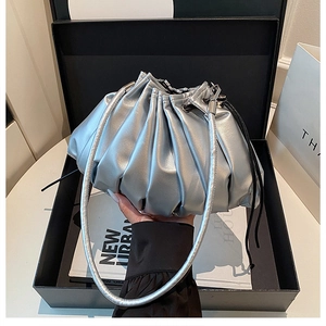 Detail of silver metallic pleated cloud bucket bag in a premium black gift box setup