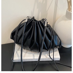 Macro shot of black pleated cloud bag with soft leather texture and drawstring detail
