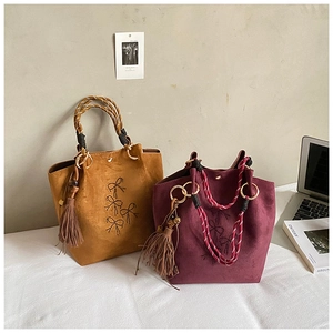 Detailaufnahme der mattierten Wildledertaschen mit Schleifenstickerei und Webgriffen
