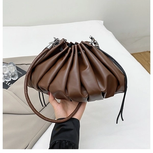Detailed close-up of brown pleated cloud bucket bag with drawstring and woven strap