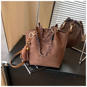 Detail der braunen Wildleder-Beuteltasche mit Strass-Schleifen und Webgriffen