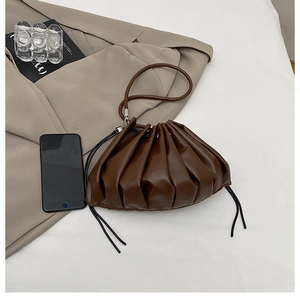 Detail of dark brown dumpling bag featuring soft pleats and a minimalist drawstring design