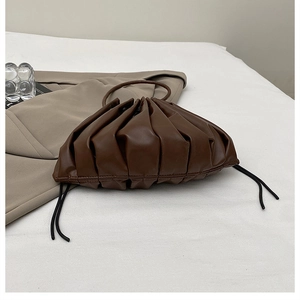 Detailed close-up of dark brown pleated dumpling bag with soft ruched cloud texture