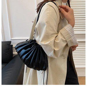 Detail view of black pleated cloud bag featuring silver metal hooks and leather shoulder strap
