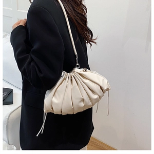 Detail of cream white pleated cloud pouch bag with soft nappa leather texture and strap