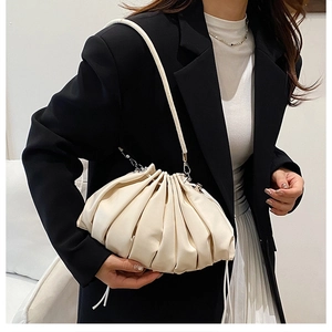 Detail of a creamy pleated cloud bag showing soft faux leather texture and slim strap