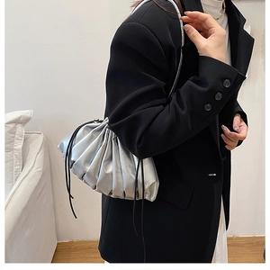 Model wearing silver pleated cloud bag with metallic finish and black crossbody drawstring