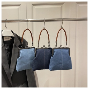 Detail of vintage denim crossbody bags with metal clasps and brown leather handles